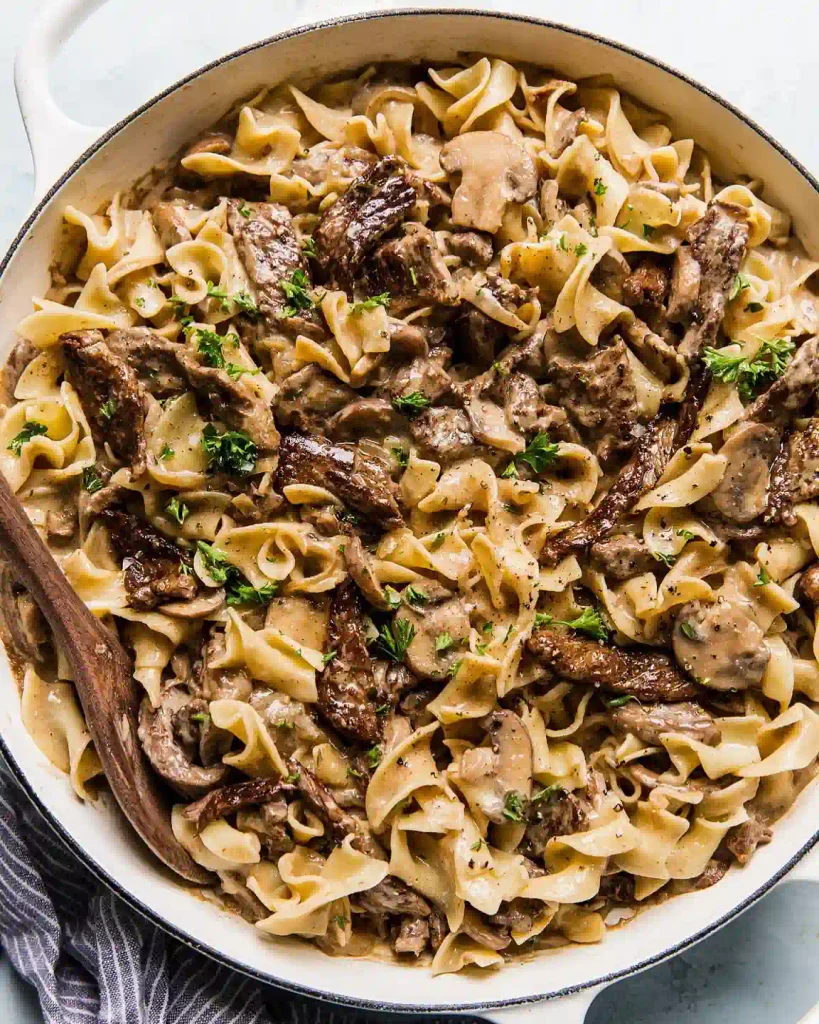 Beef Stroganoff 2 Bowl of beef stroganoff with tender beef strips over egg noodles, garnished with parsley