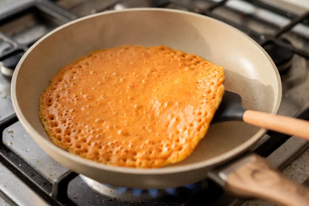 Pumpkin Pancakes 4 Pumpkin pancake batter cooking on a hot griddle, bubbles forming across the surface